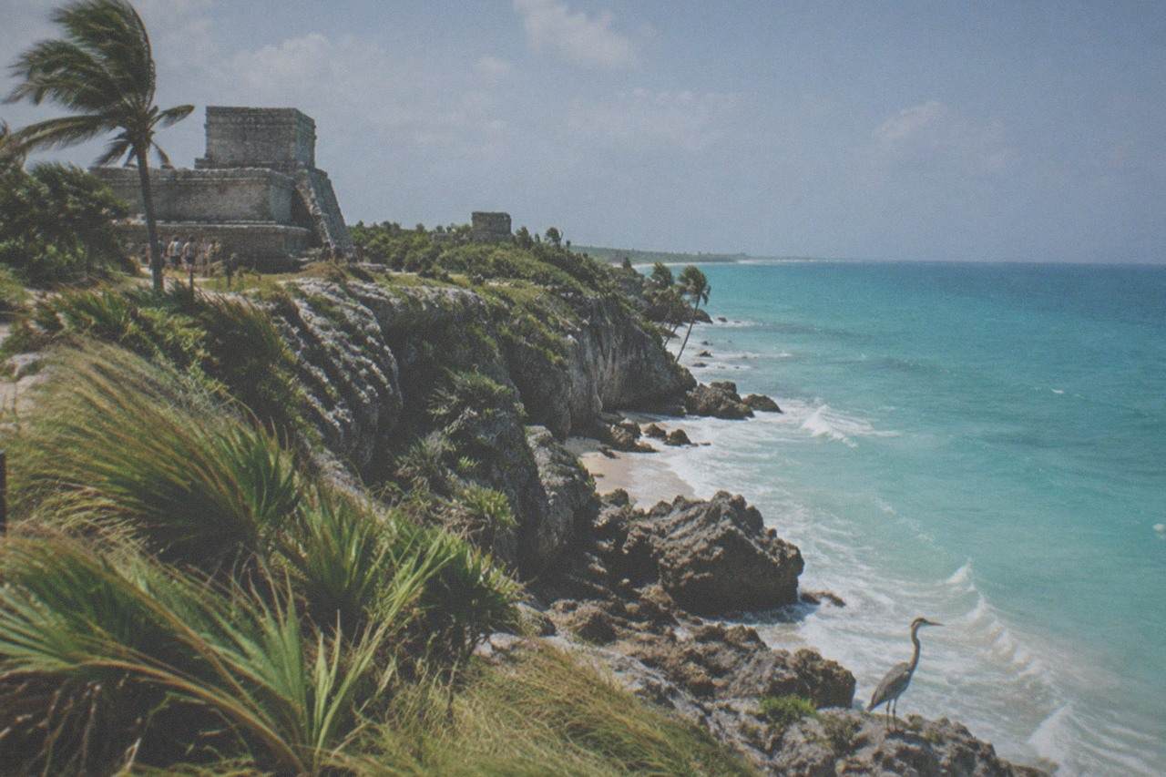 Maya stone ruins on a cliff above the Caribbean sea under a bright sky