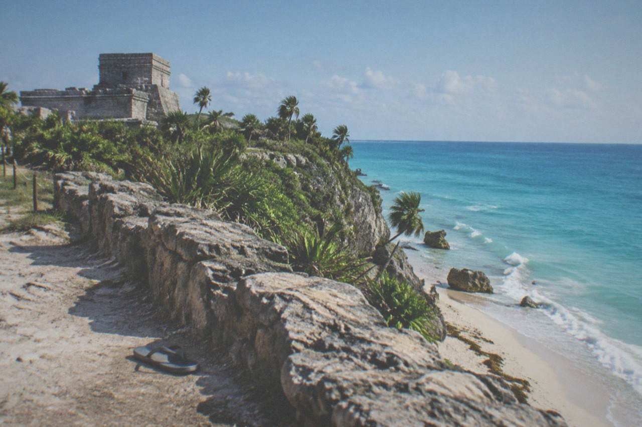 Stone walls of the Tulum archaeological site above a Caribbean cliff under a clear sky