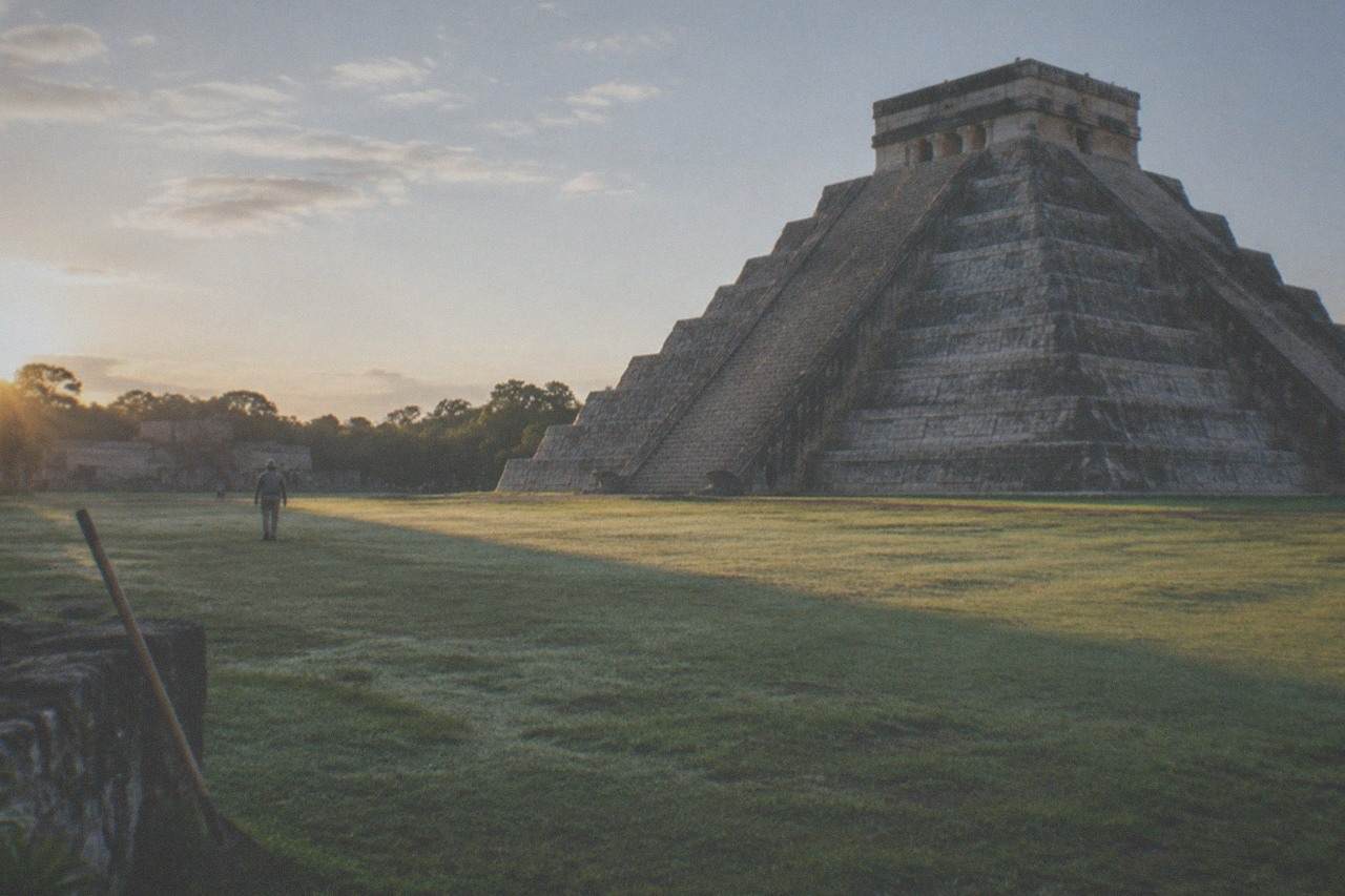 The stepped pyramid of El Castillo rising above a grassy plaza under a wide sky
