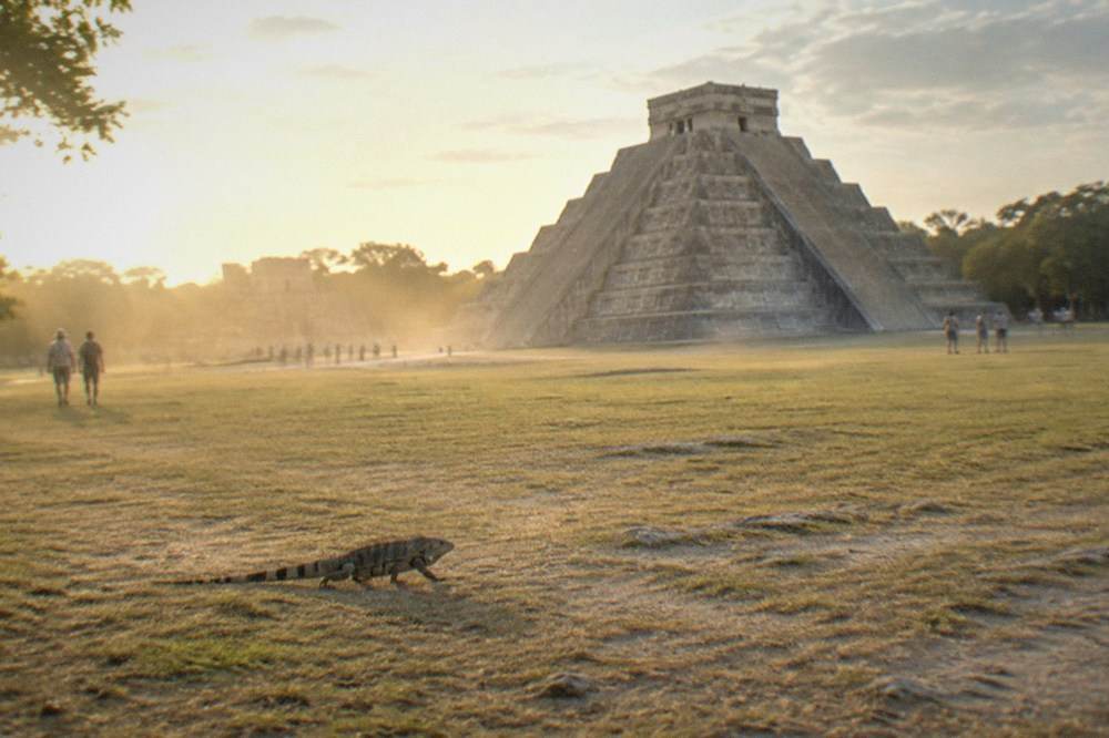 A tall stepped stone pyramid with a flat temple platform on top, seen from a distance across open ground