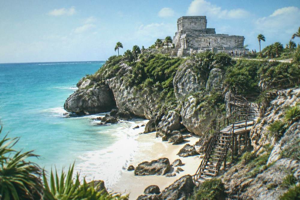 Stone watchtower ruin overlooking a quiet Caribbean cove at the Tulum archaeological site