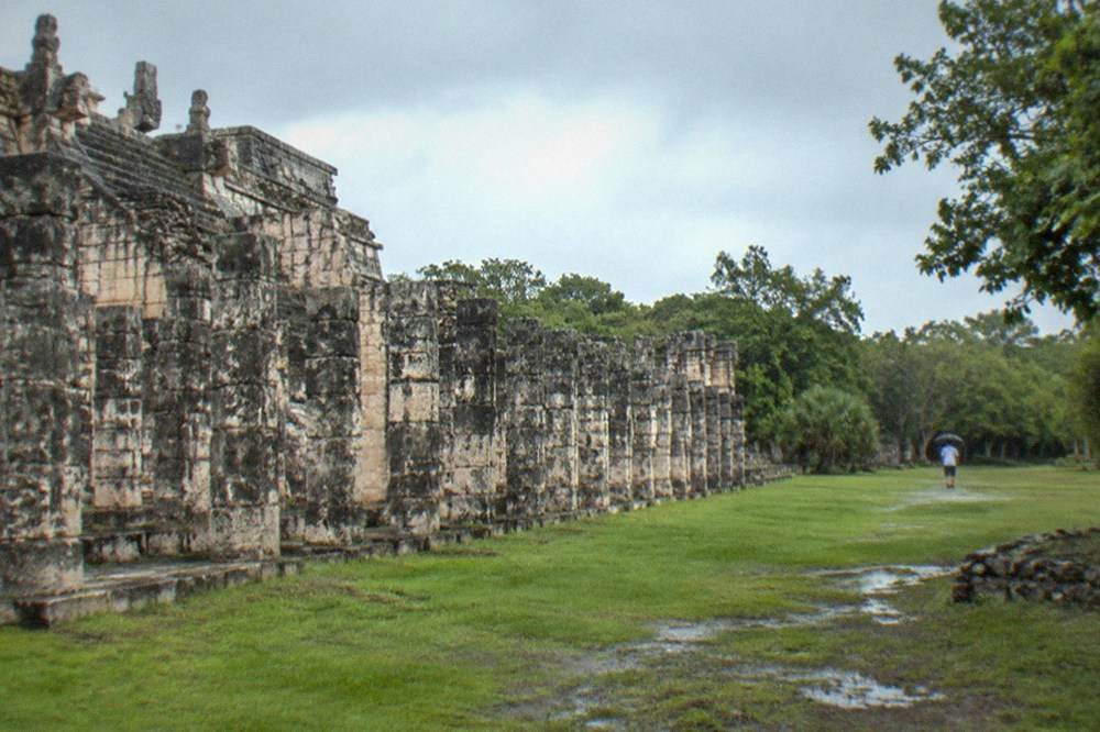 Stone columns of an ancient temple complex standing in rows on a grassy plaza
