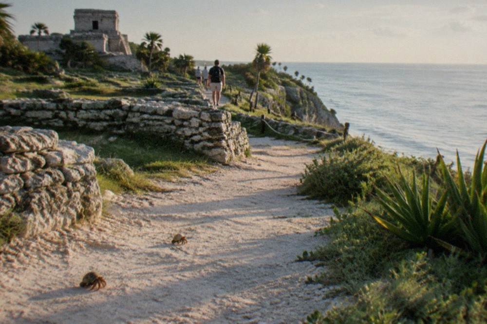 Low stone walls of a coastal archaeological site with the Caribbean sea in the background