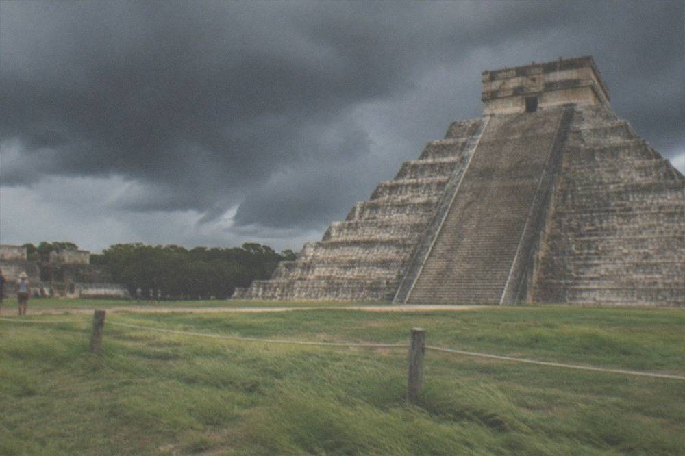 A barrier of low rope and wooden posts in front of an ancient stone pyramid staircase