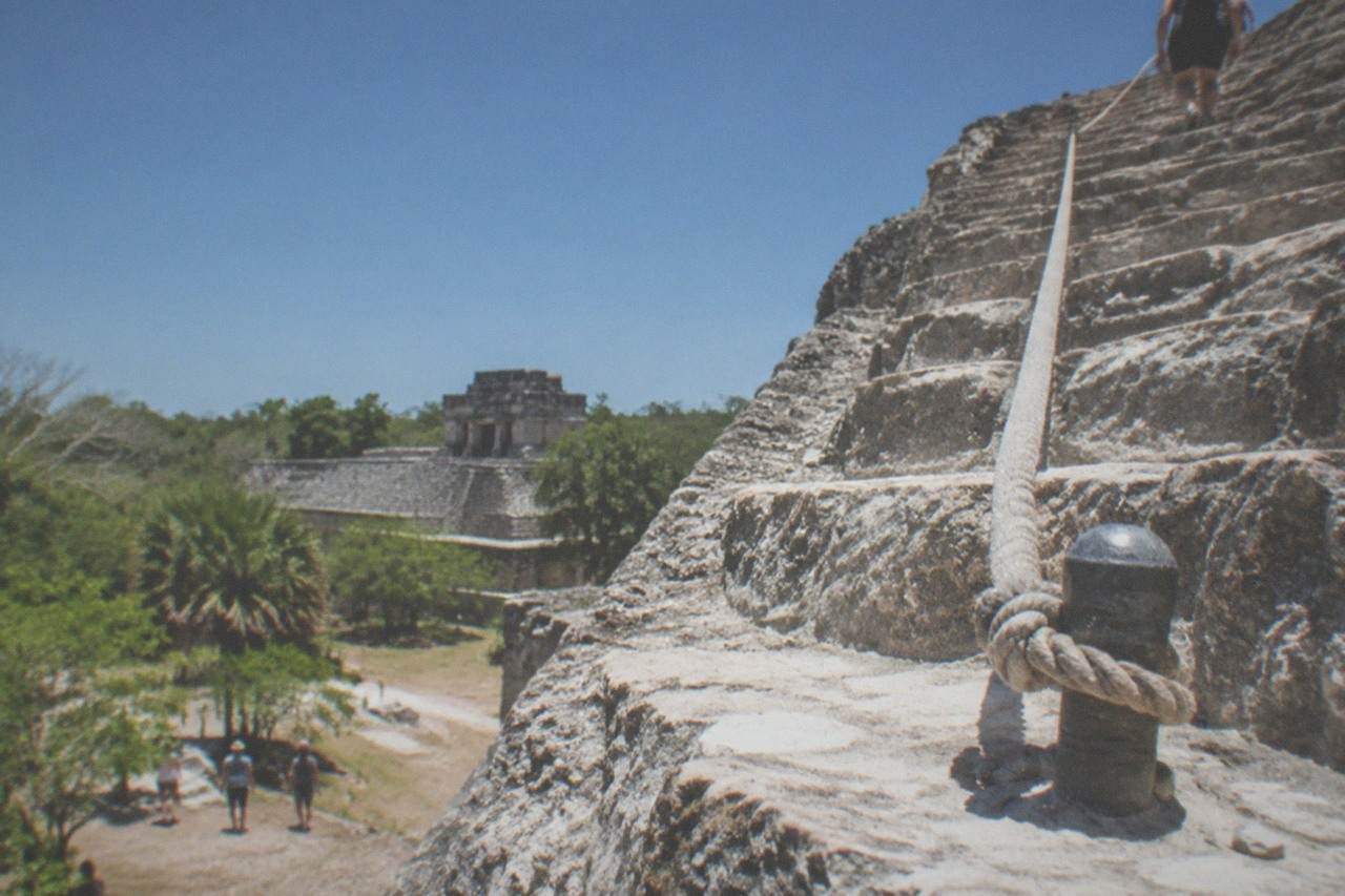 Stone steps of an ancient Mayan pyramid rising above jungle canopy under a clear sky