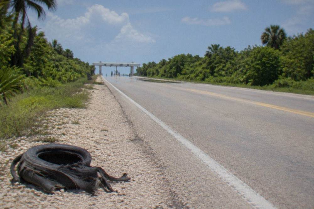 An empty toll highway cutting through flat green Yucatan jungle under a clear sky