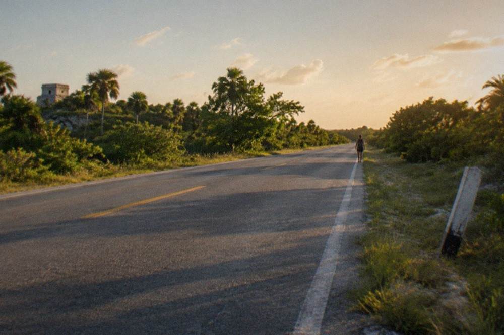 An empty toll highway cutting through flat green Yucatan jungle under a wide sky