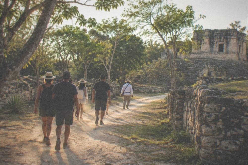 A small tour group with a guide walking on a stone path between ancient ruins buildings