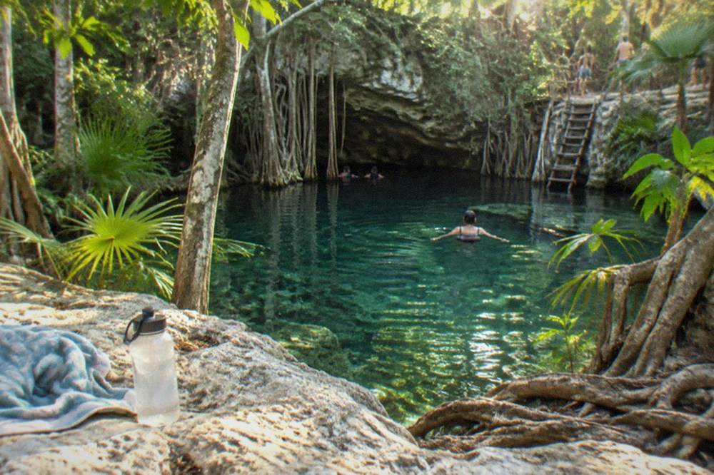 Bicycles parked on a jungle path beside a clear freshwater cenote
