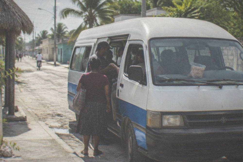 White shared van parked on a sunny street in a small Mexican town