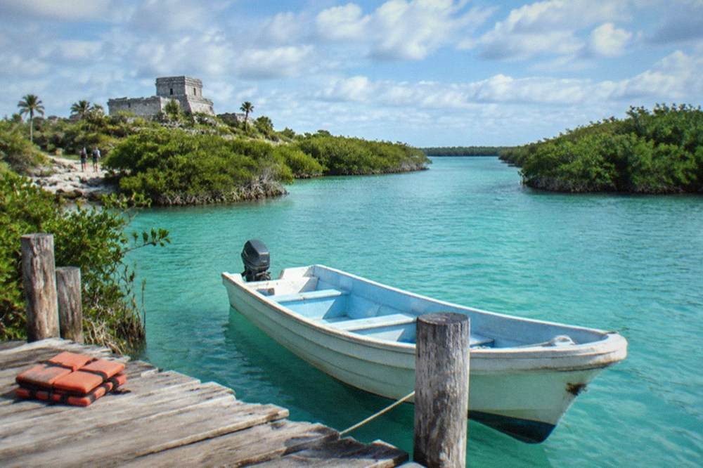 A calm turquoise lagoon surrounded by mangroves under scattered clouds