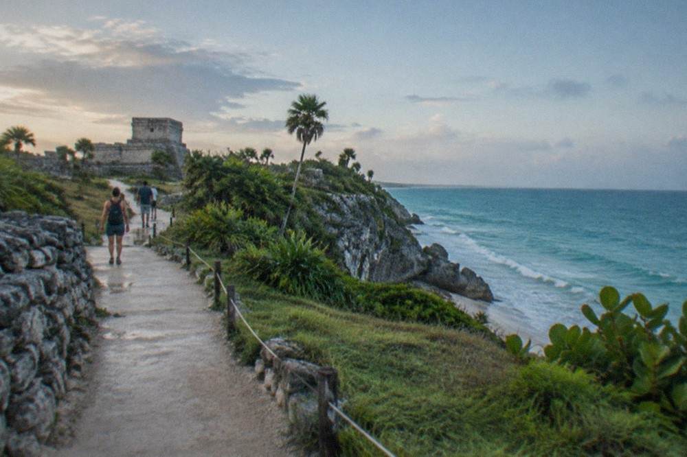 A quiet morning walkway inside the Tulum archaeological zone with the sea beyond