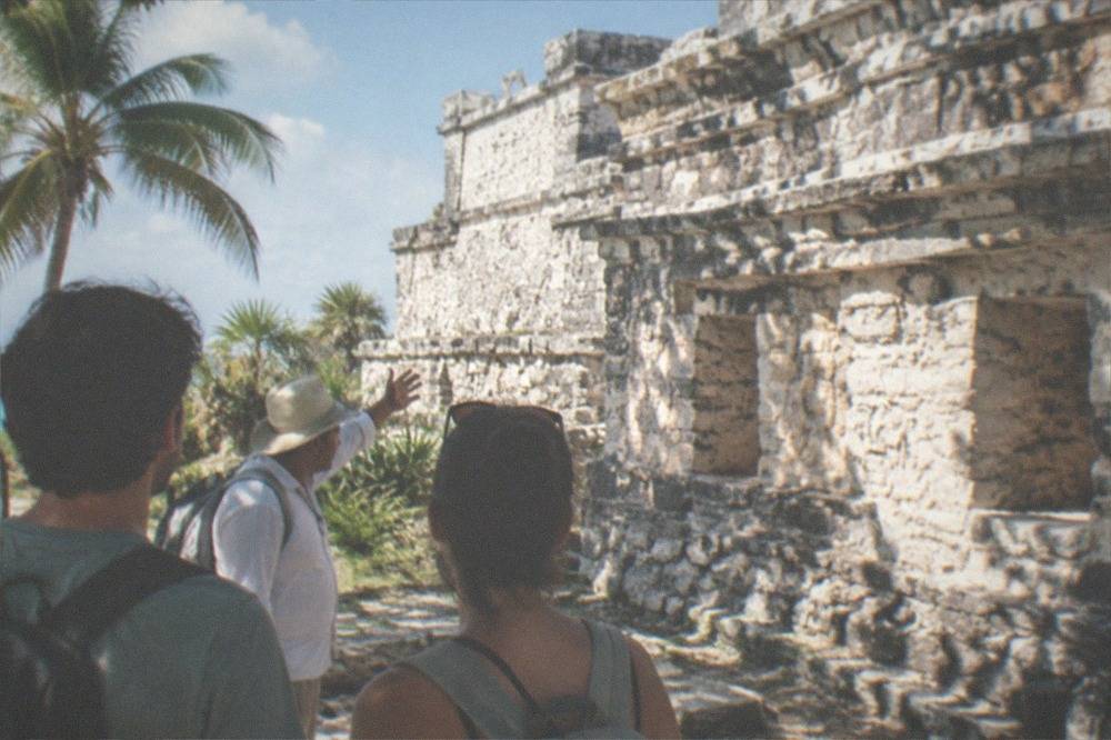 A guide speaking with a small group beside the Temple of the Frescoes at Tulum