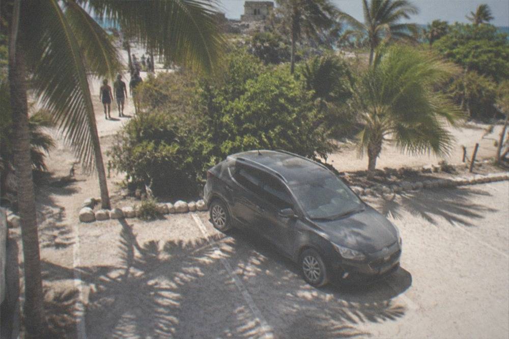 A shaded parking area with palms near the Tulum ruins highway entrance