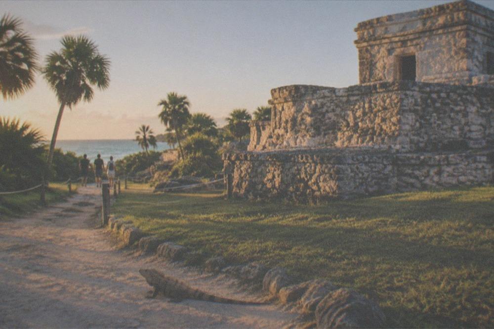 A quiet morning path inside the Tulum archaeological zone with low sun on the ruins