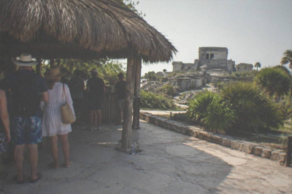 A ticket entrance area with a thatched shade structure and visitors waiting at a low counter