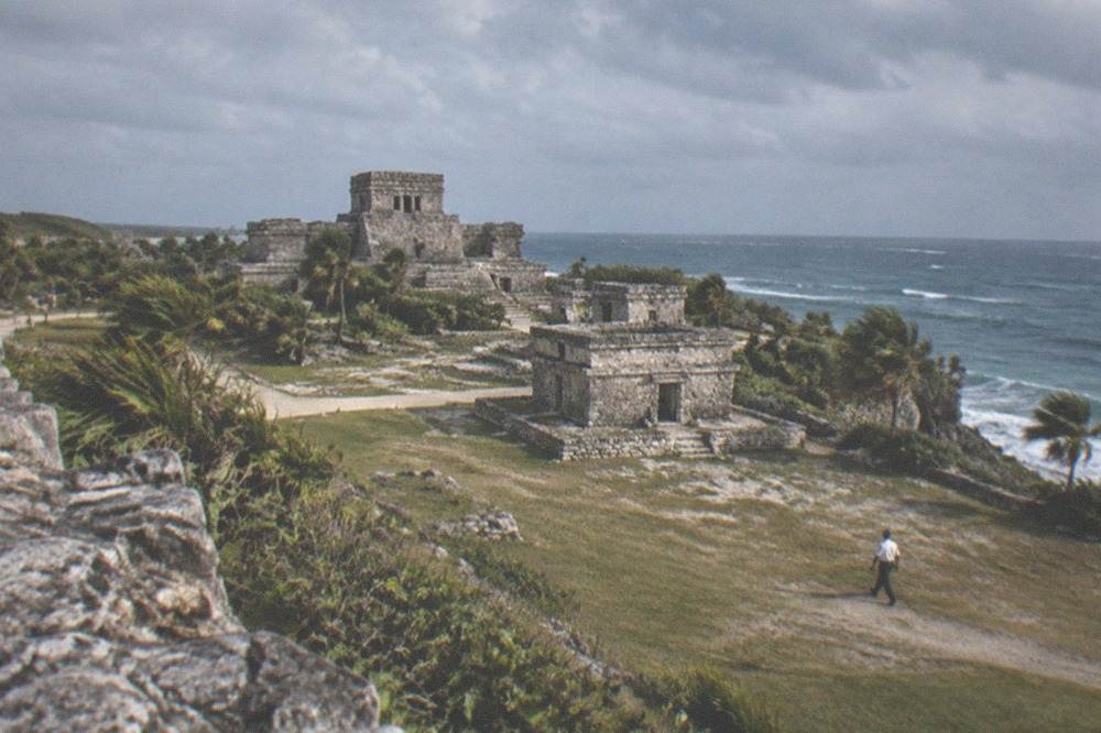 A wide view of Maya stone ruins with the Caribbean Sea in the background